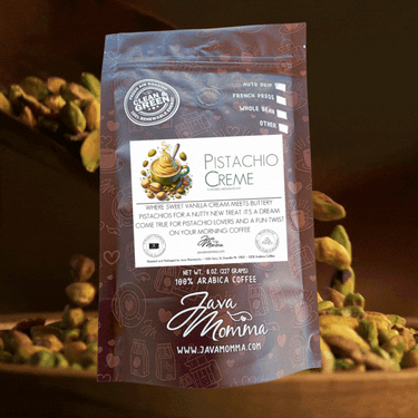 A bag of Pistachio Crème Flavored Coffee stands upright with a label showing creamy swirls and pistachios. Scattered pistachios and a wooden scoop add to the appeal—ideal for fans of this limited-edition blend.